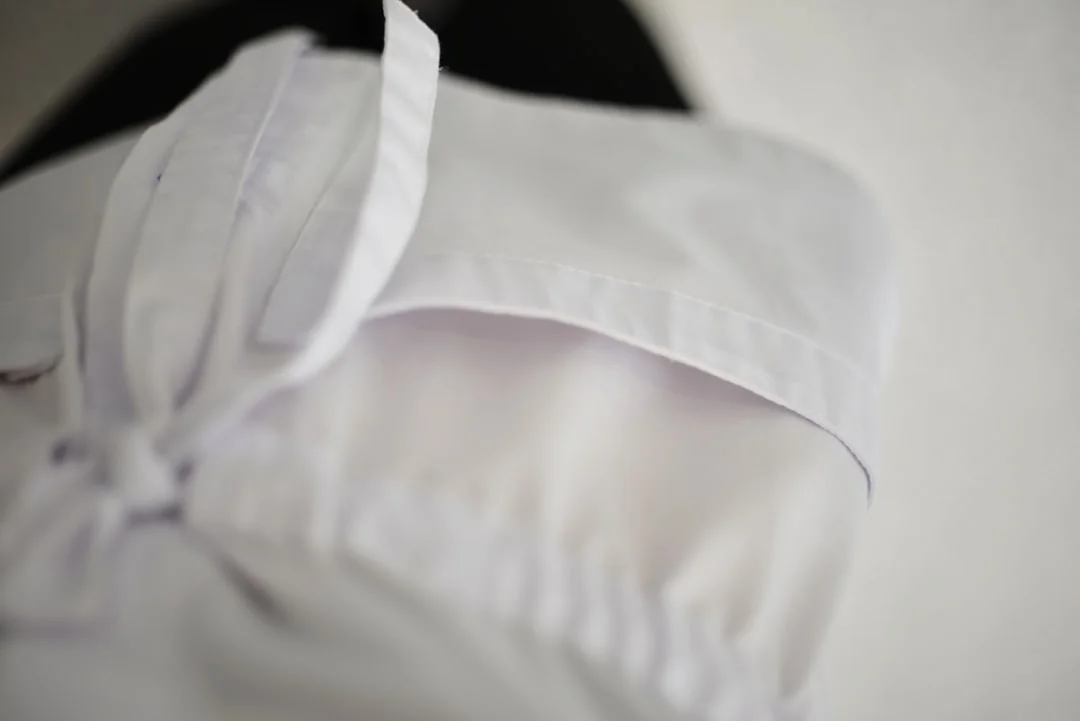 who-we-are A housekeeper in uniform skillfully arranges bed linen in a luxurious hotel room.